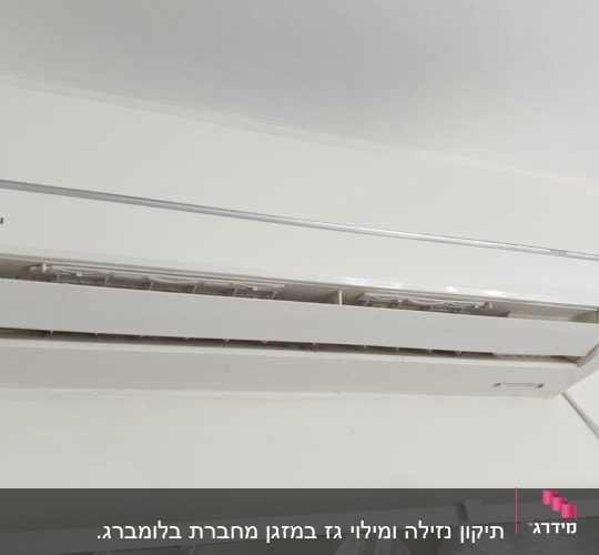 מזגן קיר לבן מותקן על קיר עם כבל חשמל